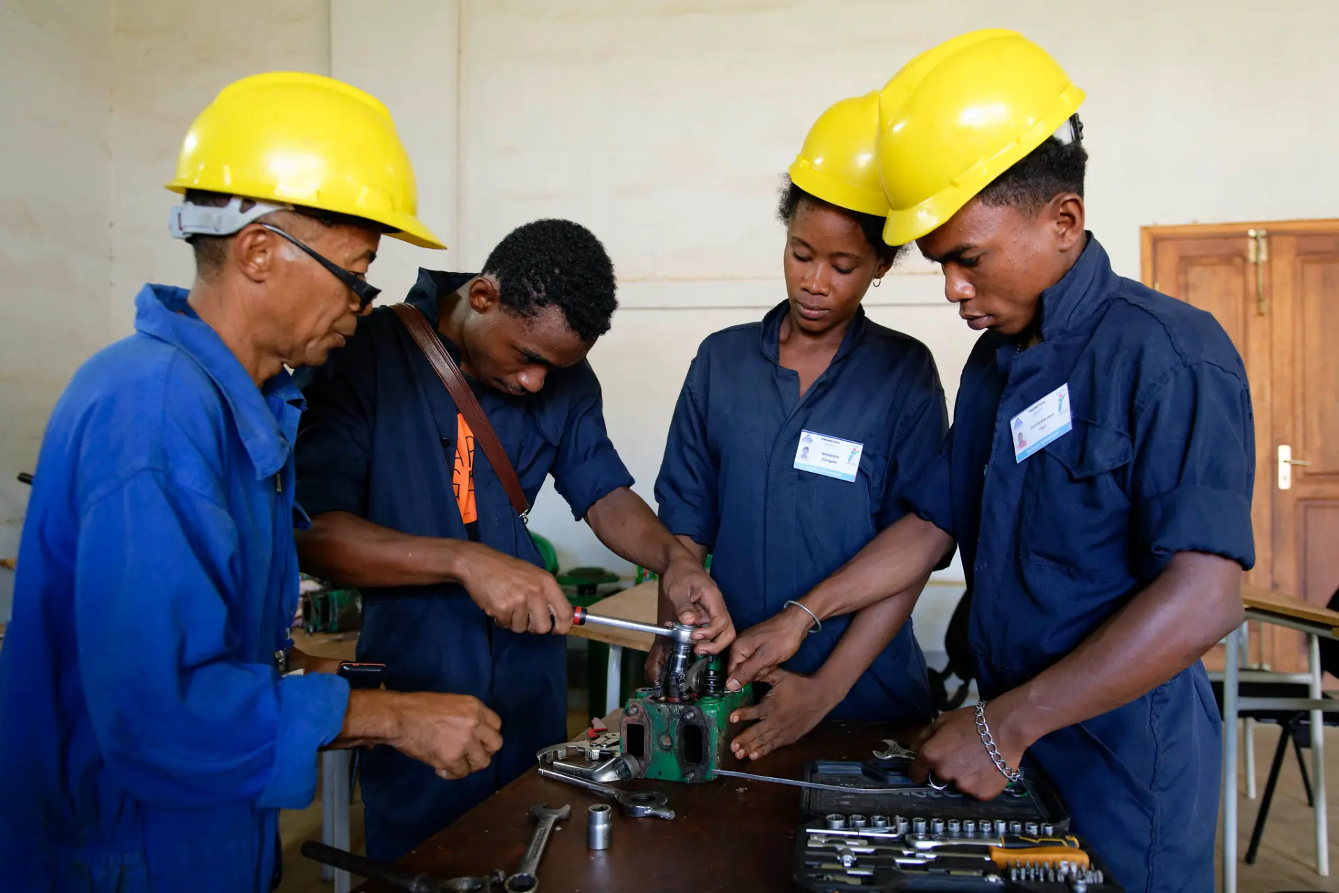 Trainees in coveralls and hard hats examining equipment during hands-on technical training