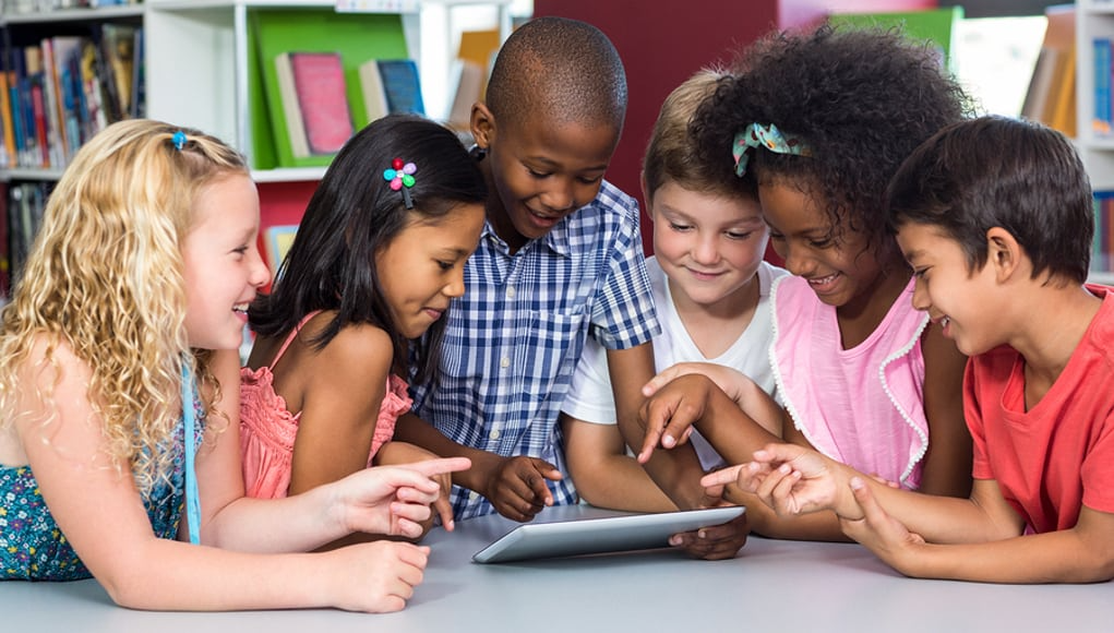 Younger students gathered around a tablet during a career exploration activity